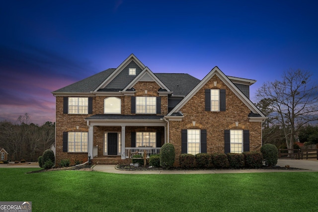 view of front of house with a front yard, covered porch, and brick siding