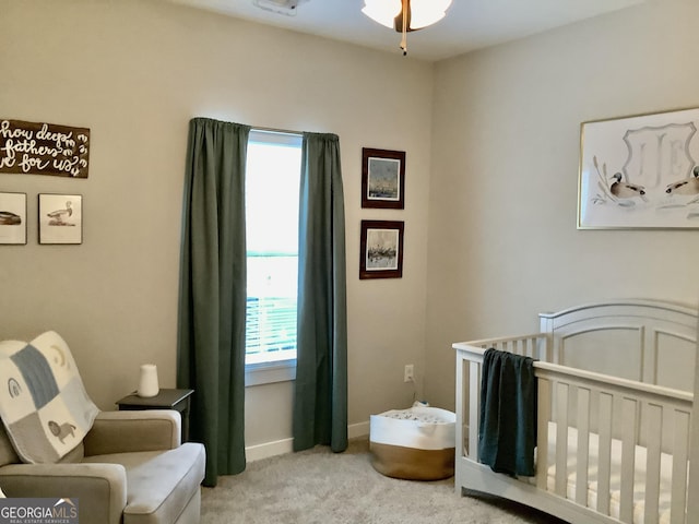 bedroom with a nursery area, light carpet, and baseboards