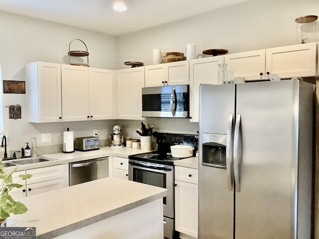 kitchen with white cabinetry, stainless steel appliances, a sink, and light countertops