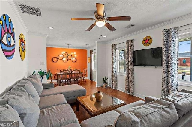 living area with a wealth of natural light, wood finished floors, visible vents, and crown molding