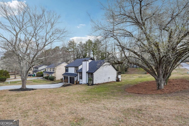 exterior space with driveway, a shingled roof, an attached garage, and a front yard