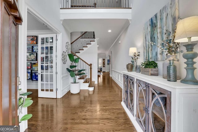 foyer entrance featuring crown molding, a towering ceiling, wood finished floors, and stairs