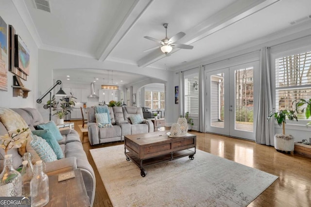 living area featuring a ceiling fan, french doors, beamed ceiling, and a healthy amount of sunlight