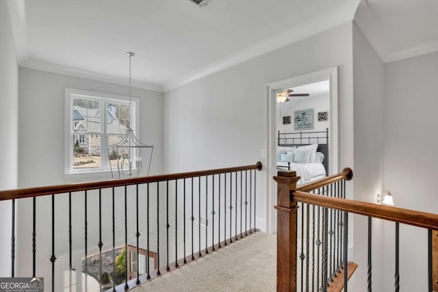 hall featuring baseboards, ornamental molding, carpet, and a notable chandelier