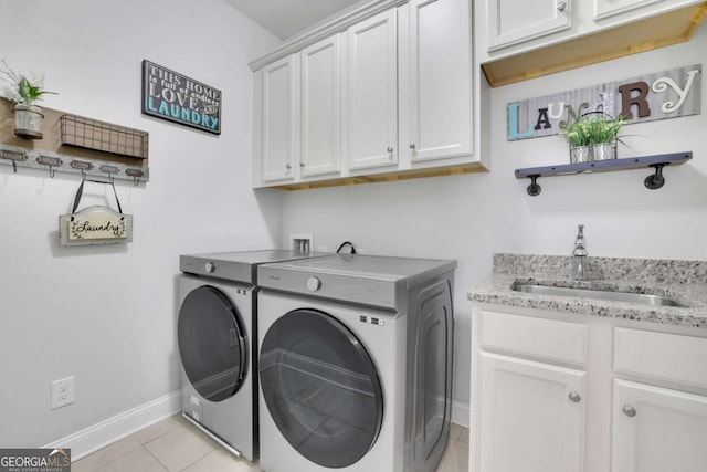 washroom with baseboards, a sink, cabinet space, washer and clothes dryer, and light tile patterned flooring