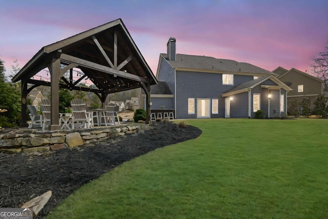 rear view of property with a yard, a gazebo, a patio, and a chimney