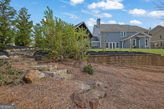 rear view of property with a chimney and a lawn