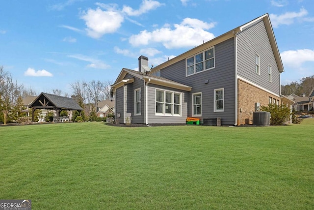 back of house featuring a chimney, central AC, a gazebo, and a lawn