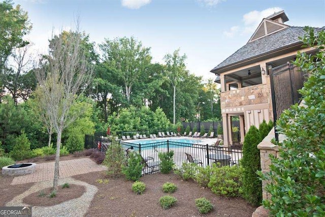 community pool with a patio area, a fire pit, and fence