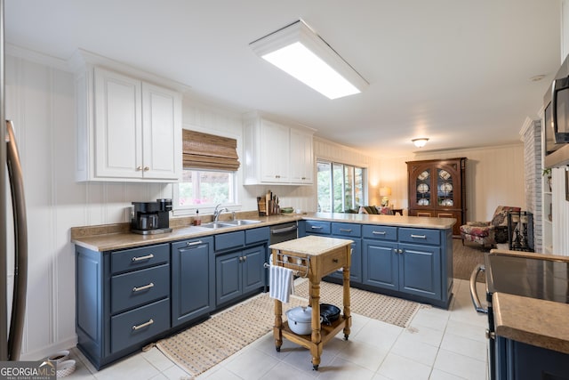 kitchen with a peninsula, blue cabinetry, white cabinetry, and a sink