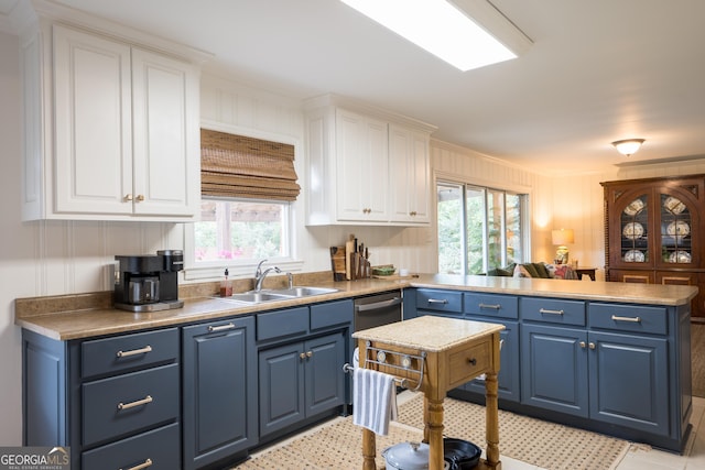 kitchen featuring ornamental molding, white cabinetry, a sink, blue cabinets, and a peninsula