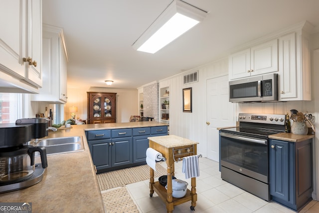 kitchen featuring appliances with stainless steel finishes, visible vents, a sink, and blue cabinetry