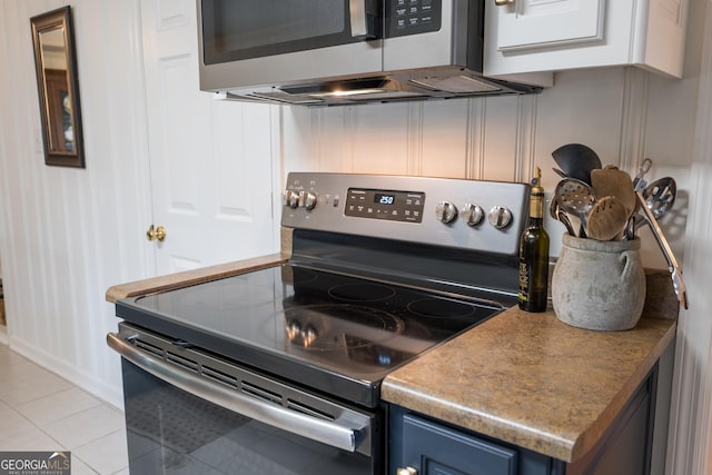 kitchen featuring blue cabinetry, light tile patterned floors, and stainless steel appliances