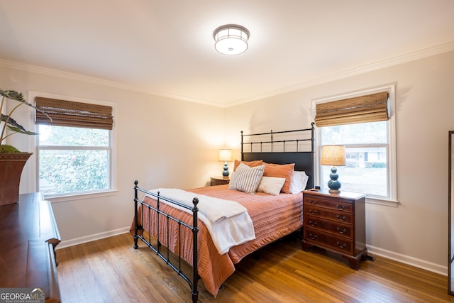 bedroom featuring crown molding, baseboards, and wood finished floors