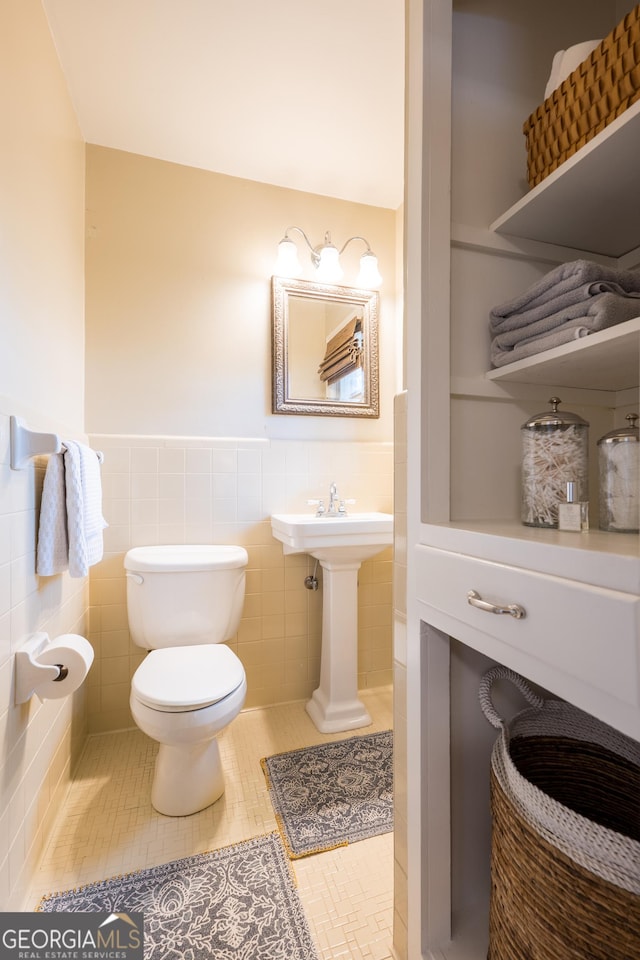 bathroom with wainscoting, tile patterned flooring, toilet, and tile walls