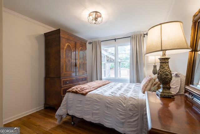 bedroom featuring ornamental molding, wood finished floors, and baseboards