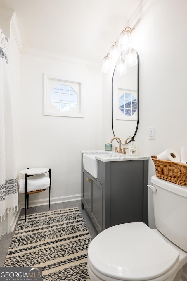 bathroom with tile patterned flooring, toilet, vanity, baseboards, and ornamental molding