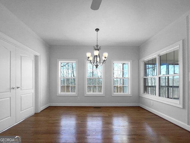 unfurnished dining area featuring visible vents, a notable chandelier, baseboards, and wood finished floors