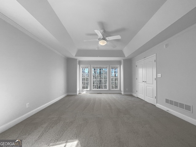 carpeted empty room featuring baseboards, visible vents, ceiling fan, and a tray ceiling