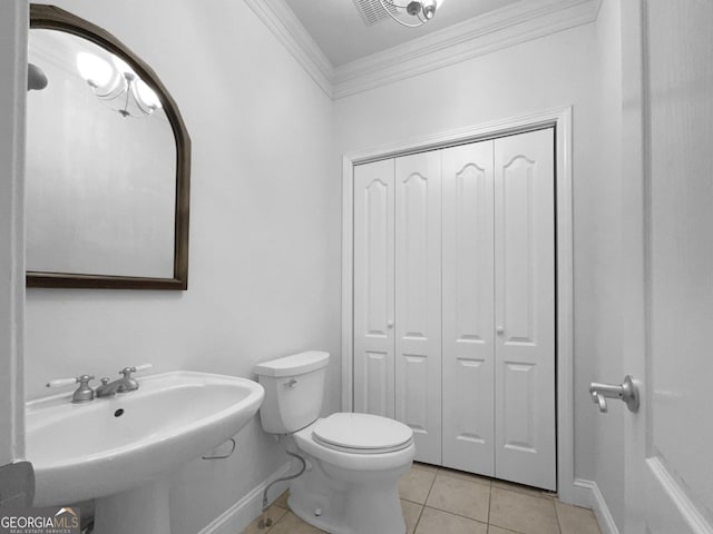 bathroom featuring tile patterned flooring, toilet, a sink, ornamental molding, and a closet