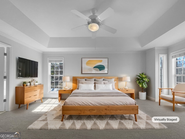 carpeted bedroom with multiple windows, a tray ceiling, and crown molding