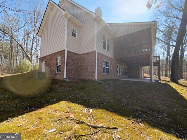 rear view of house featuring brick siding, a patio, and a chimney