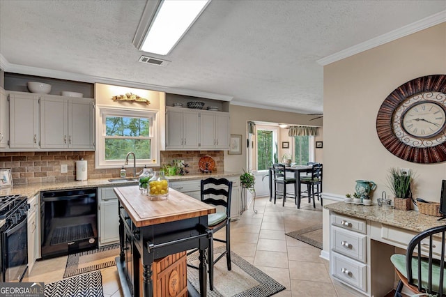 kitchen featuring visible vents, ornamental molding, black appliances, a sink, and light tile patterned flooring