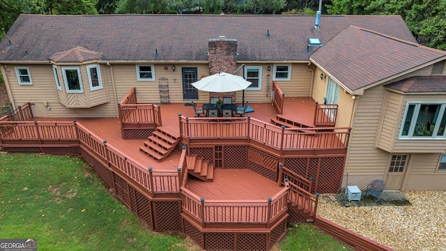 rear view of property featuring a deck, a yard, and outdoor dining area