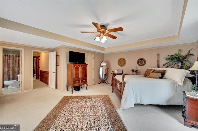 bedroom featuring ensuite bathroom, a raised ceiling, and light colored carpet