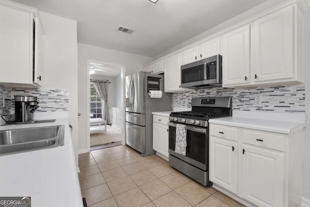 kitchen featuring appliances with stainless steel finishes, light tile patterned flooring, visible vents, and white cabinets