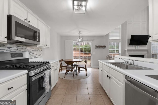 kitchen featuring white cabinets, appliances with stainless steel finishes, decorative backsplash, and a sink