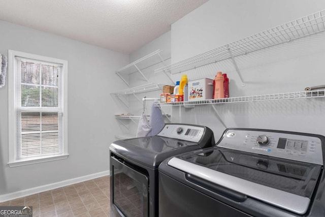 laundry area featuring a textured ceiling, laundry area, washer and clothes dryer, and baseboards