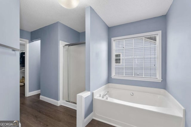 full bathroom with a spacious closet, a shower stall, a bath, and wood finished floors