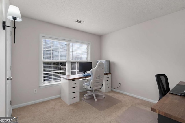 home office with light carpet, a textured ceiling, visible vents, and baseboards