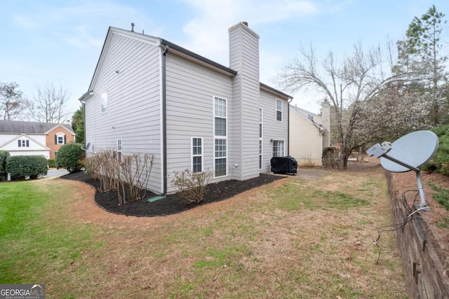 view of side of property with a chimney and a yard