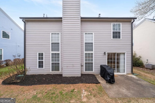 back of house featuring a patio, a chimney, and cooling unit