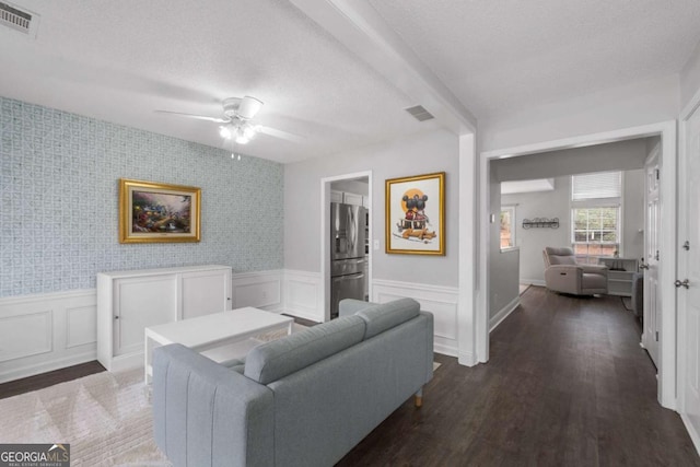 living room with a textured ceiling, wainscoting, and visible vents