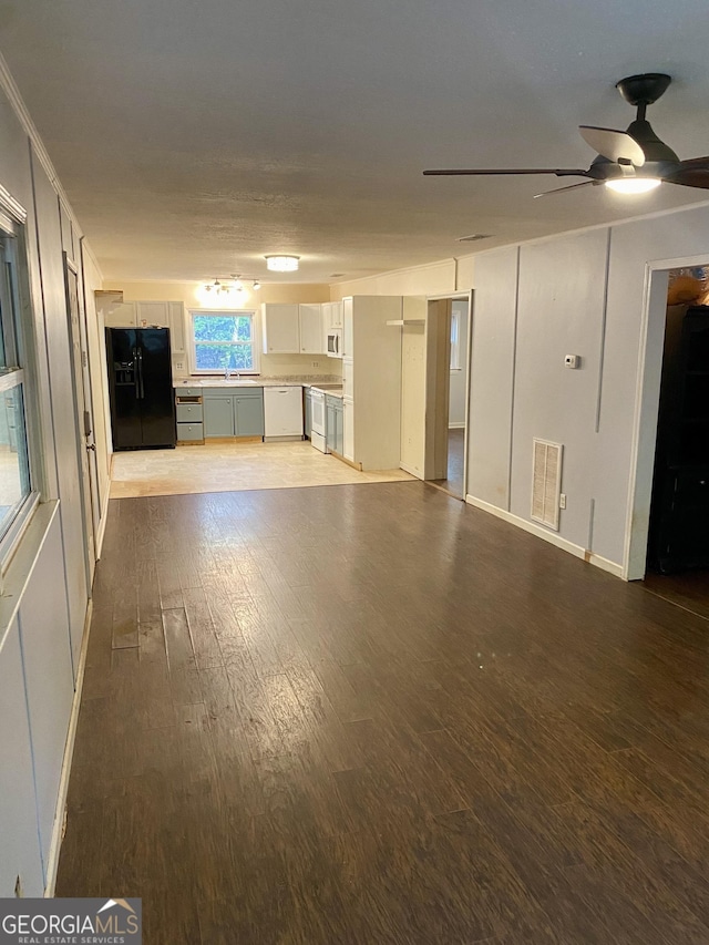 unfurnished living room featuring baseboards, ceiling fan, wood finished floors, and visible vents