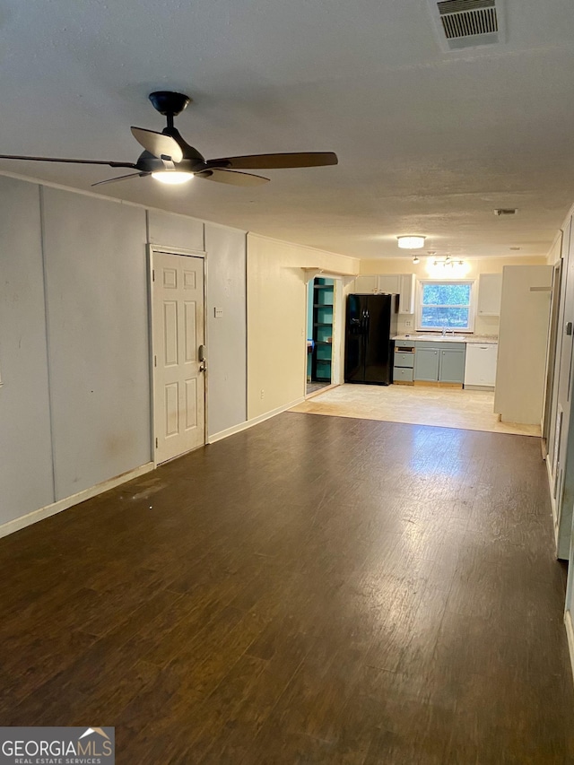 unfurnished living room featuring visible vents, a ceiling fan, a sink, and wood finished floors