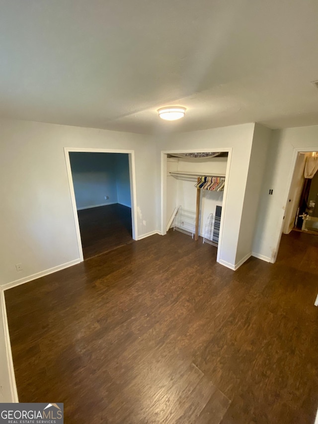 unfurnished bedroom with baseboards, wood finished floors, and a closet
