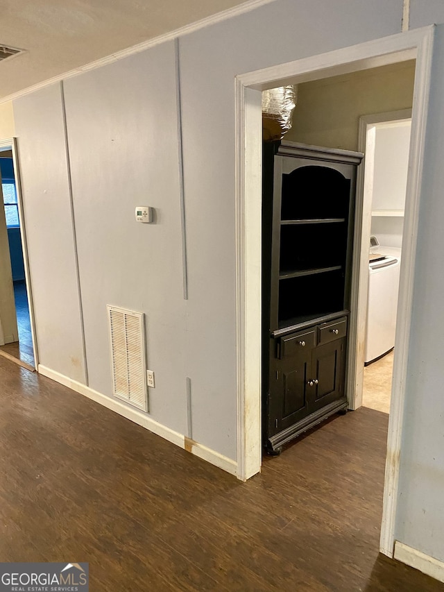 hallway with visible vents, ornamental molding, washer / dryer, baseboards, and dark wood-style floors