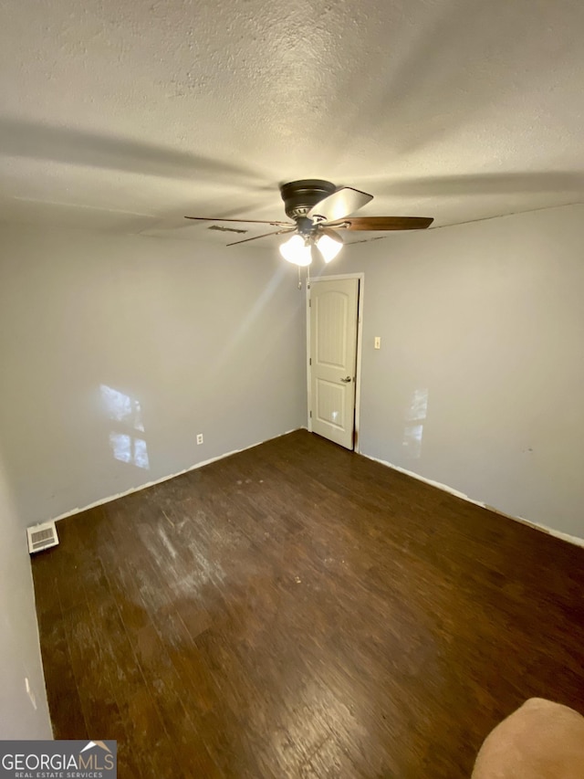 empty room featuring visible vents, a textured ceiling, ceiling fan, and wood finished floors