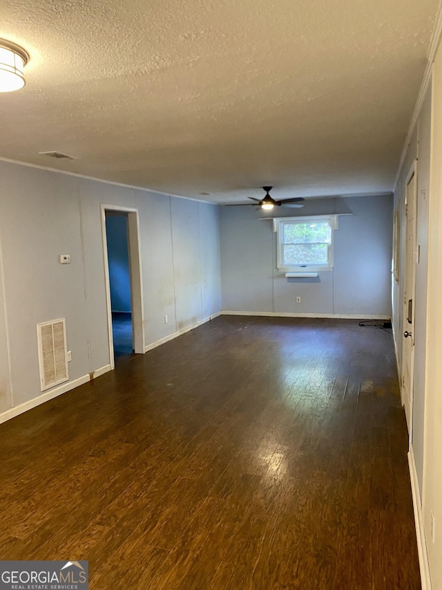 spare room with a ceiling fan, dark wood-type flooring, a textured ceiling, and visible vents