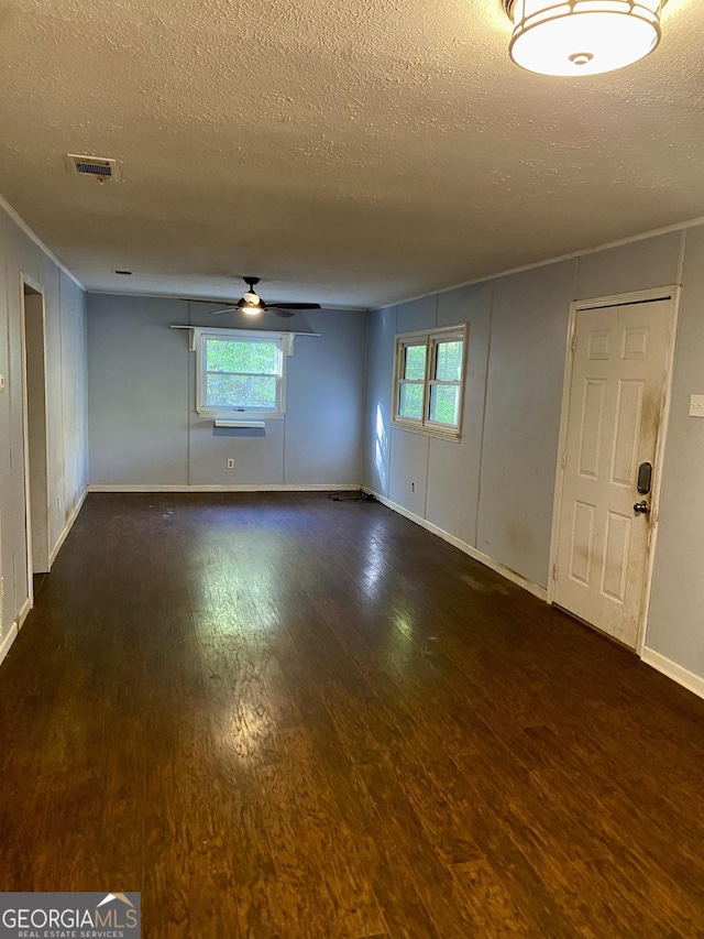 empty room featuring a wealth of natural light, a ceiling fan, a textured ceiling, and wood finished floors