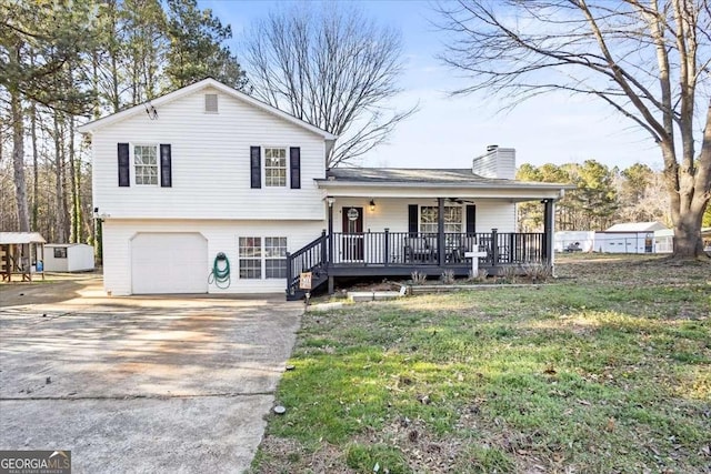 split level home with concrete driveway, a front lawn, a chimney, and an attached garage