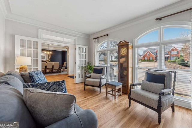 interior space featuring ornamental molding, french doors, a notable chandelier, and light wood-style flooring