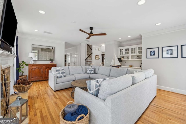 living area featuring a fireplace with raised hearth, light wood finished floors, stairway, and recessed lighting