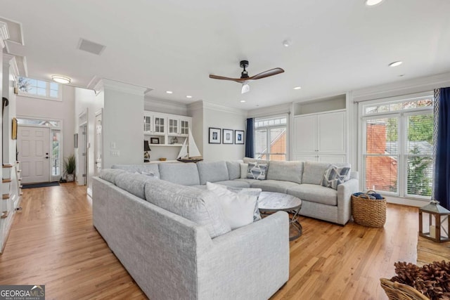 living area with ornamental molding, plenty of natural light, and light wood-style flooring