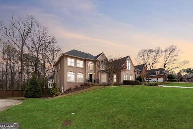 view of front of property featuring a front lawn, fence, and stucco siding