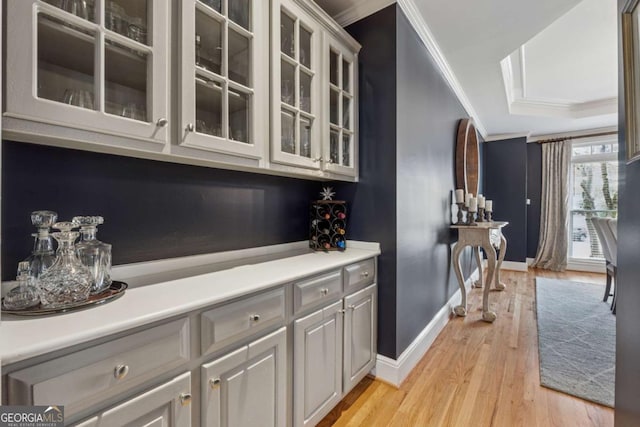 bar featuring light wood-style floors, baseboards, and ornamental molding